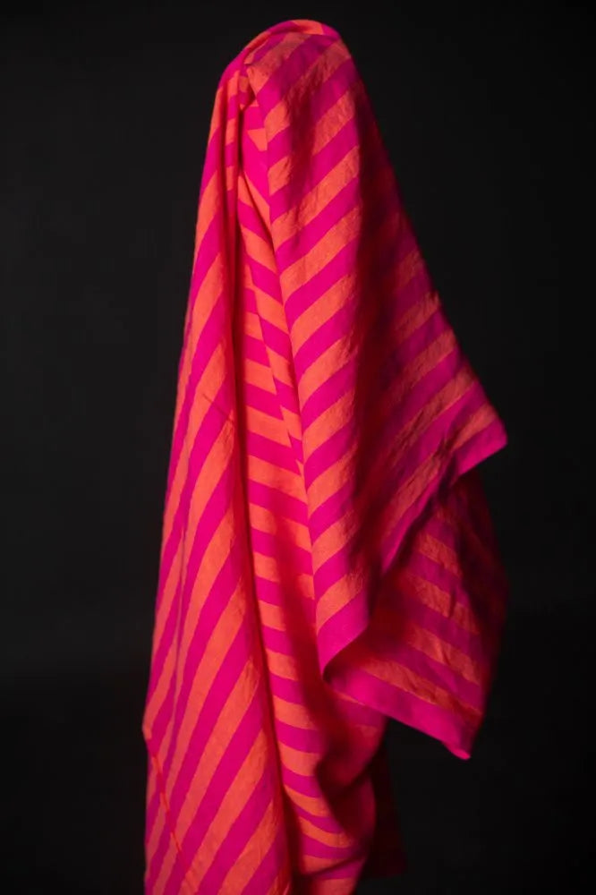 Pink and orange striped fabric draped over a black background