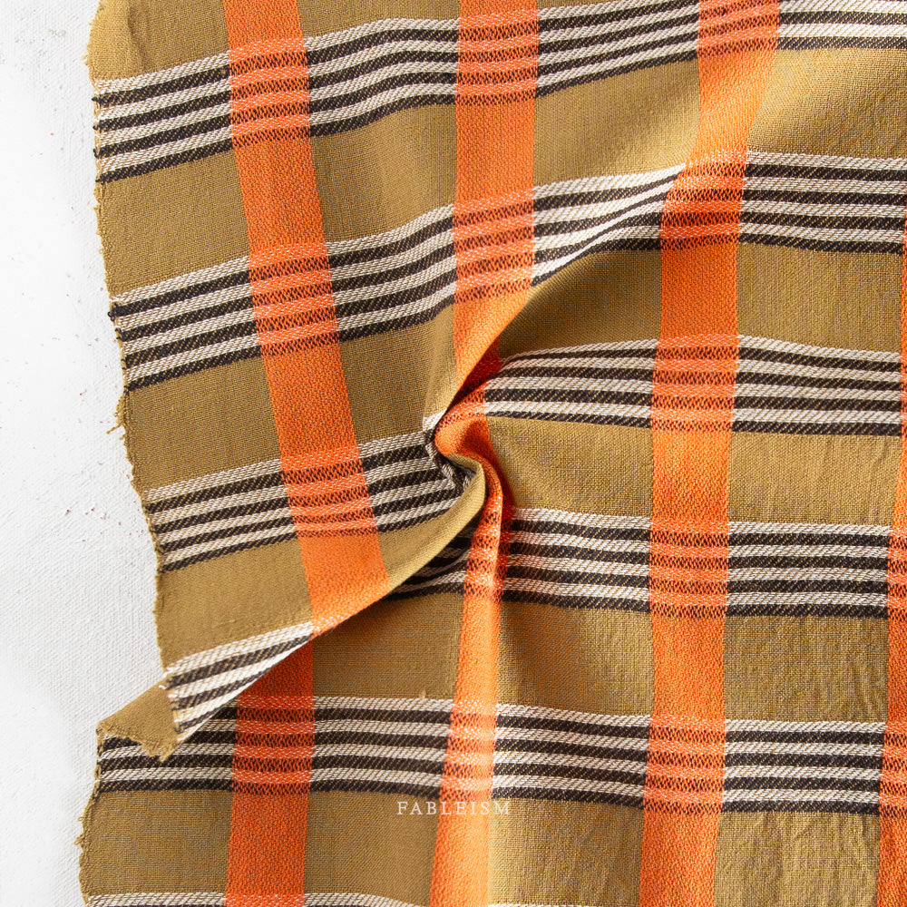 Plaid fabric with orange, brown, and black stripes on a white background