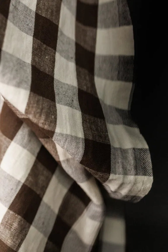 Close-up of plaid fabric with brown, white, and gray colors on a dark background