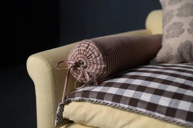 Decorative pillow with plaid pattern on a beige sofa against a dark background