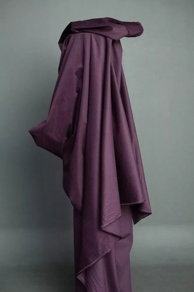 Purple fabric draped over a form against a gray background